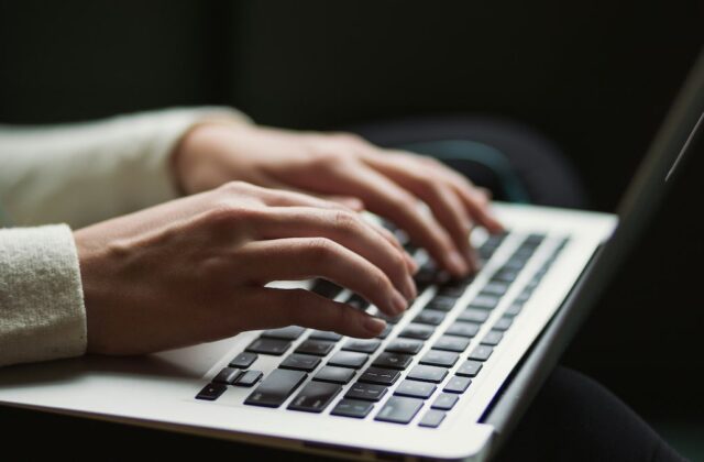 Close view of a medical transcriptionist's hands on their laptop.