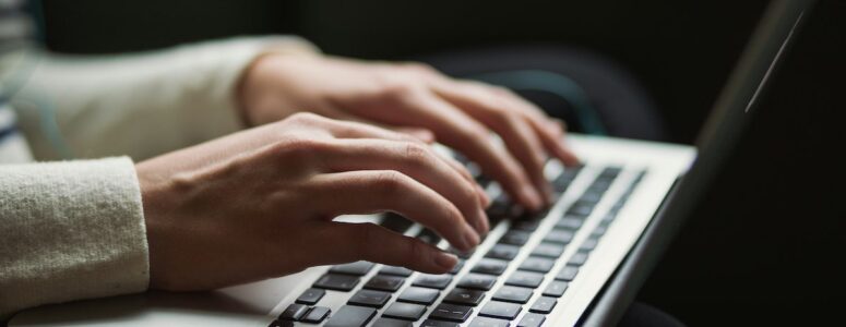 Close view of a medical transcriptionist's hands on their laptop.