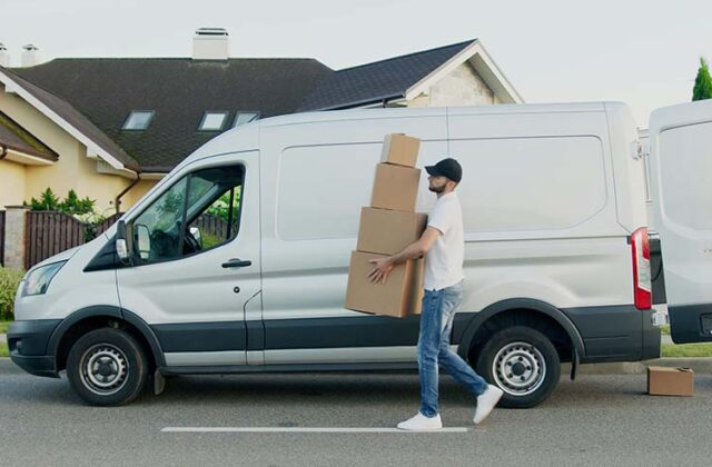 Professional mover carrying boxes outside a moving van.