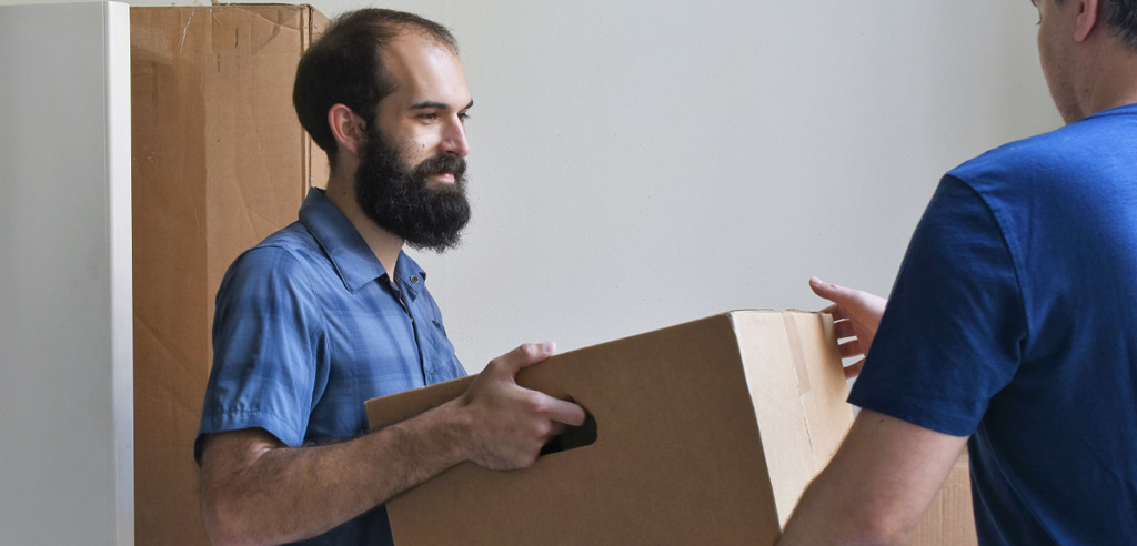 Part-time mover handing a box to someone in their new home