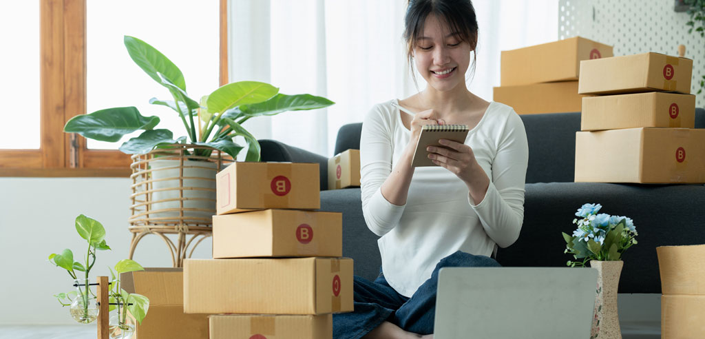 Solo online seller writing labels on a box in her home