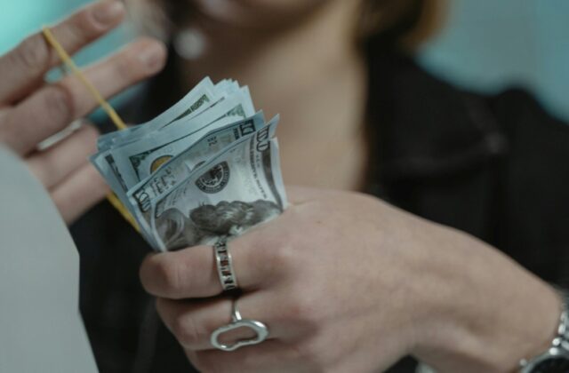 Woman scrounging up bills to pay payday loan fees in a rubber band.
