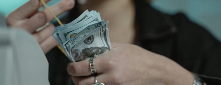 Woman scrounging up bills to pay payday loan fees in a rubber band.