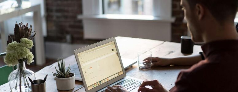 Man at his desk using his laptop to pick a side hustle.