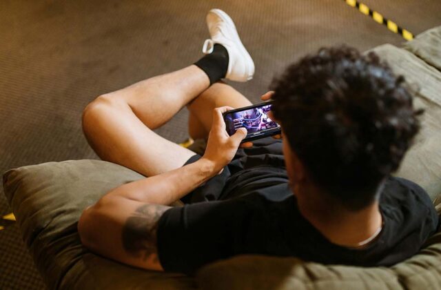 Man sitting in a chair betting on a mobile game on his smartphone.