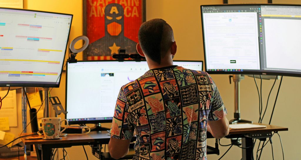 A tired polyworker stares at multiple screens with different applications showing. 