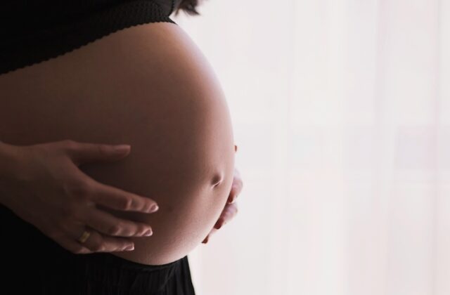 Pregnant woman cradling her belly.