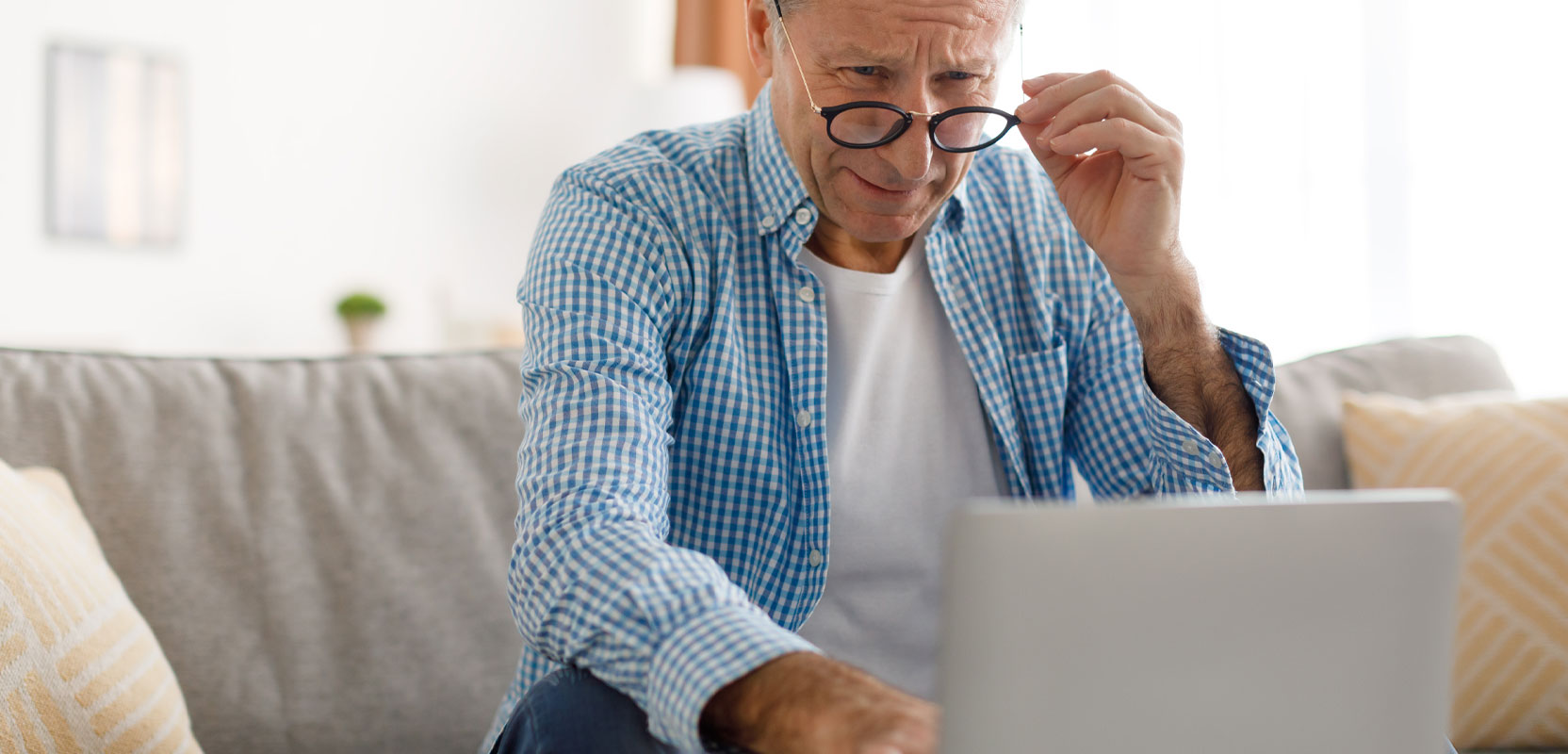 Elderly man sitting at a laptop proofreading an article 