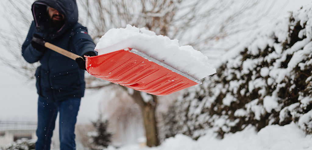 a lawn professional is shoveling snow during winter