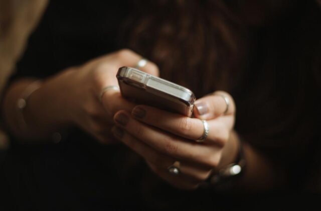 Close view of a woman holding a smartphone and using a side hustle app.