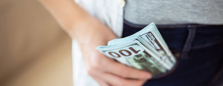 Close view of someone holding a stack of hundred-dollar bills