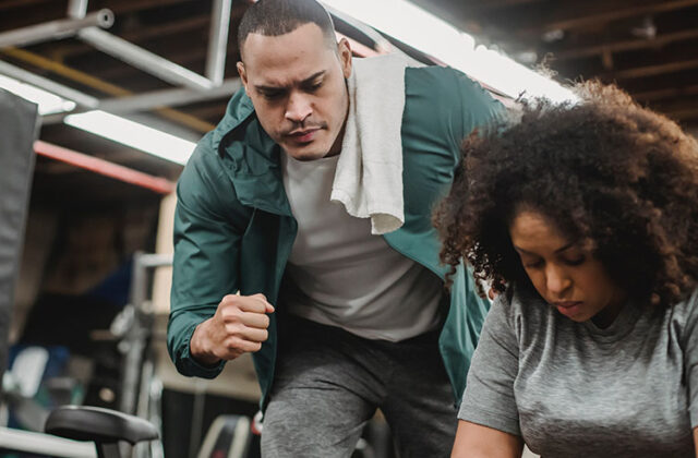 Personal trainer watching carefully and cheering on a client at the gym