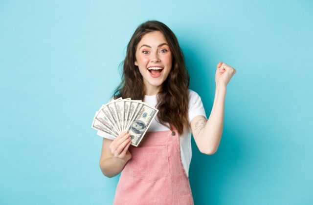Young woman smiling with lots of cash in hand.