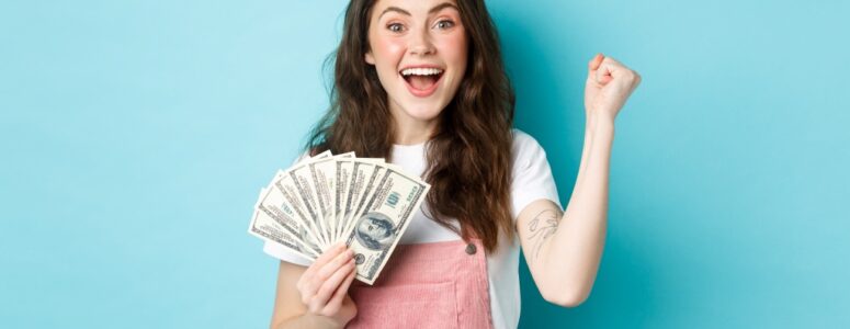 Young woman smiling with lots of cash in hand.