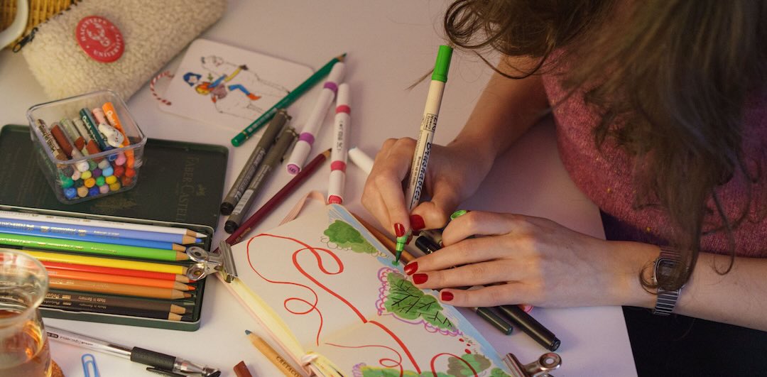 Woman drawing in a notebook for her snail mail business.