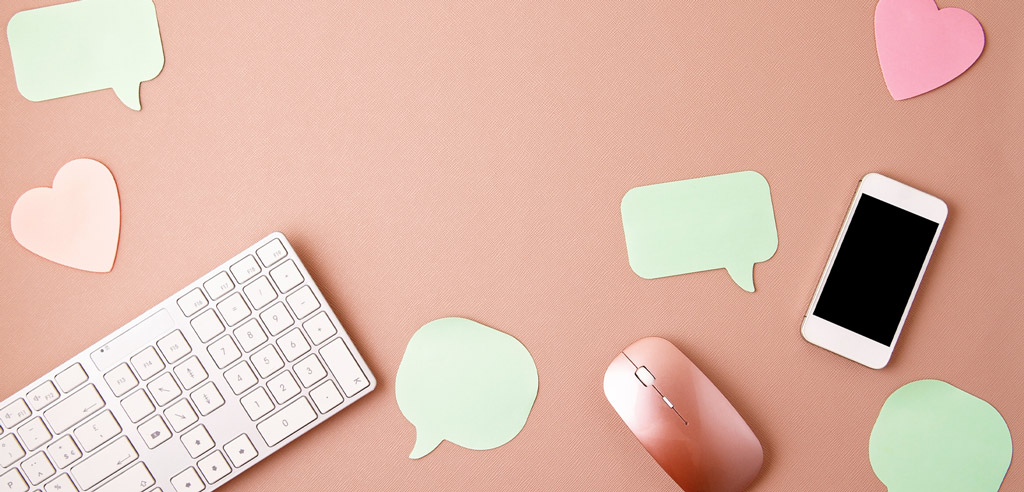 Keyboard, phone, and stickers shaped like speech bubbles representing a social media side hustle that you can do from home
