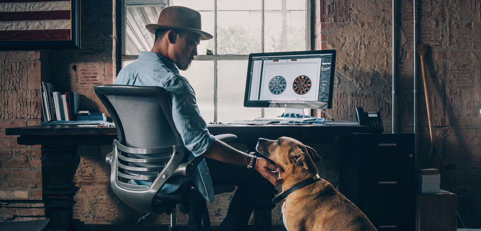 Man sitting at a computer petting his dog and working on setting up a dog-walking business