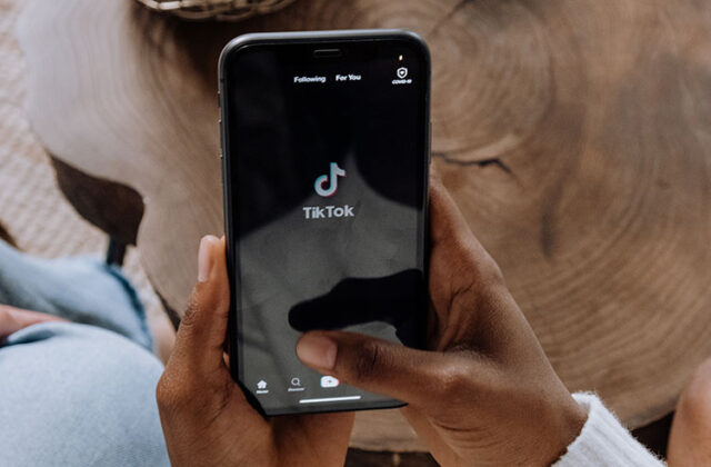 Person holding a mobile phone showing the TikTok logo for the TikTok referral program