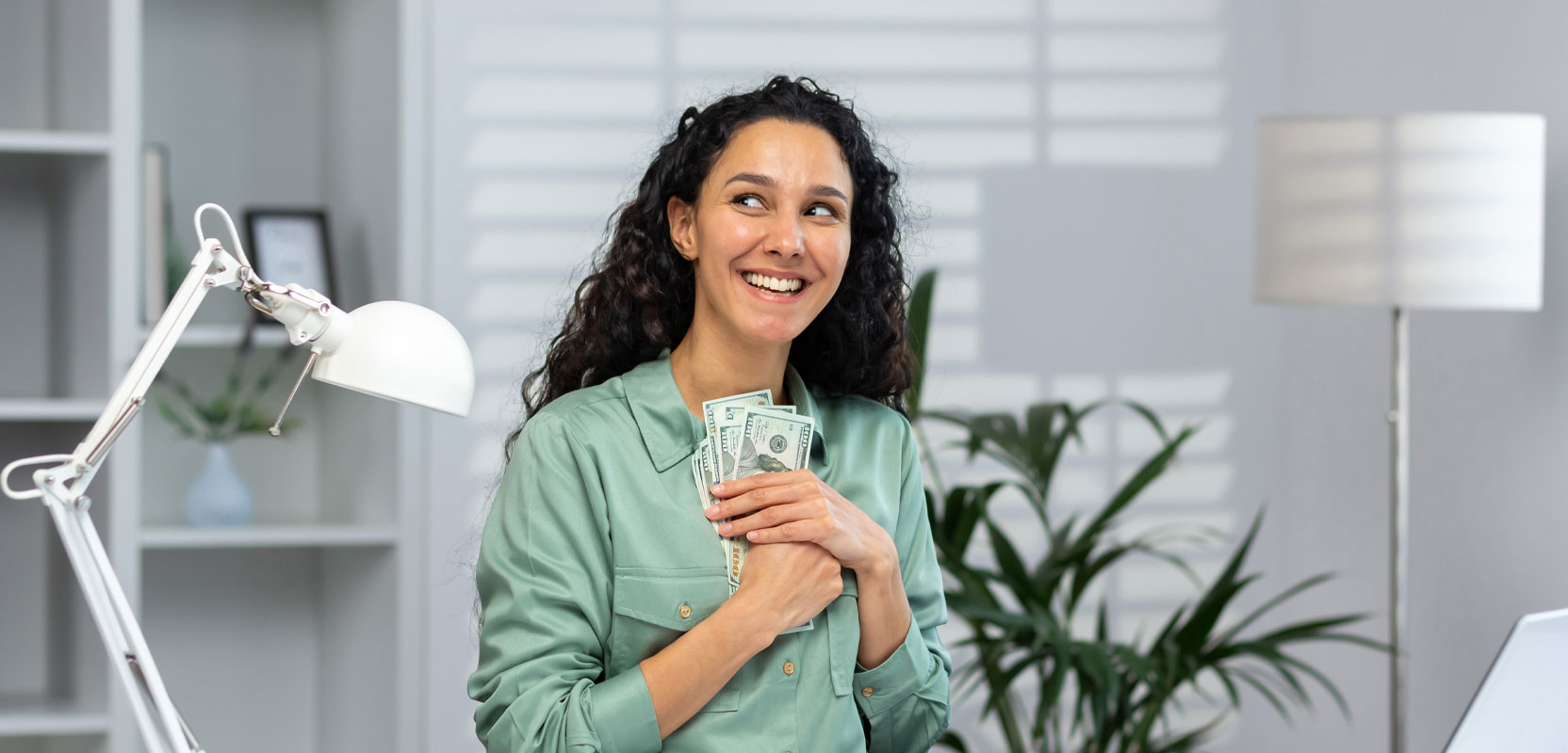Woman holding cash to her chest and smiling