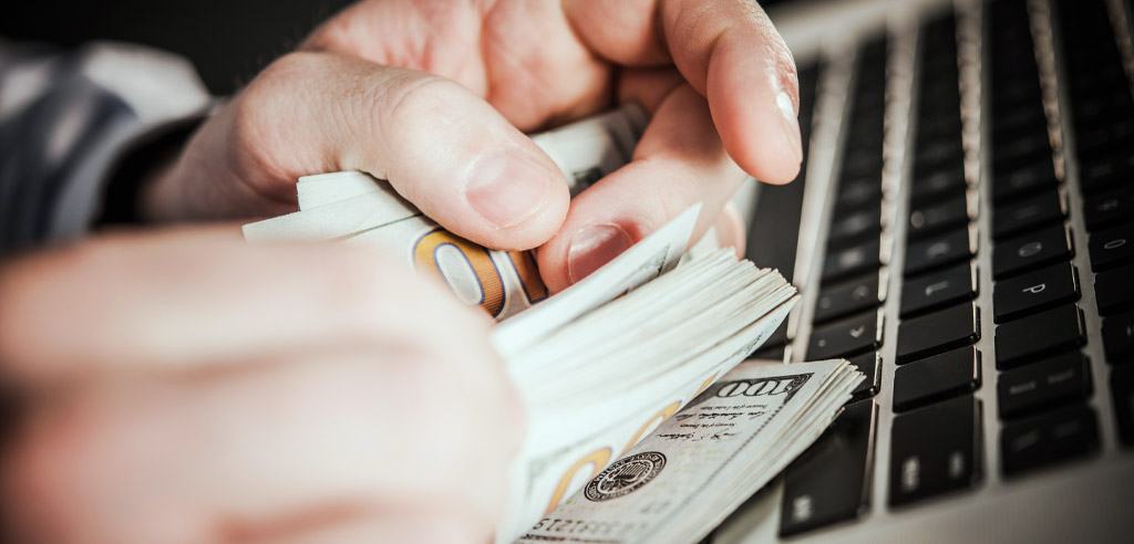 Close view of hands holding a large stack of hundred-dollar bills