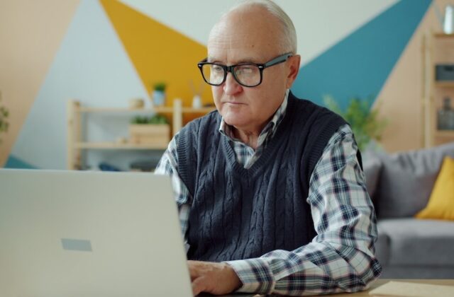 A retirement-age man working on a computer.