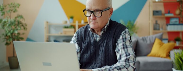 A retirement-age man working on a computer.