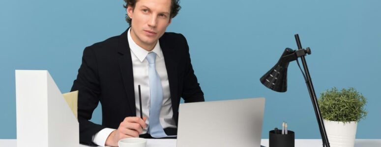 Professional consultant in a suit looking thoughtful and sitting at a white desk with a laptop and mug