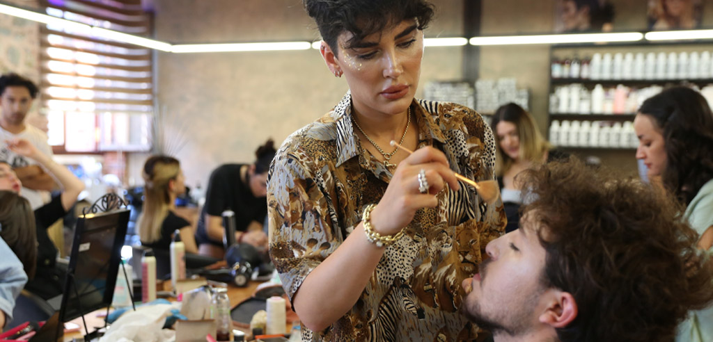 Freelance makeup artist using a makeup brush on a male client