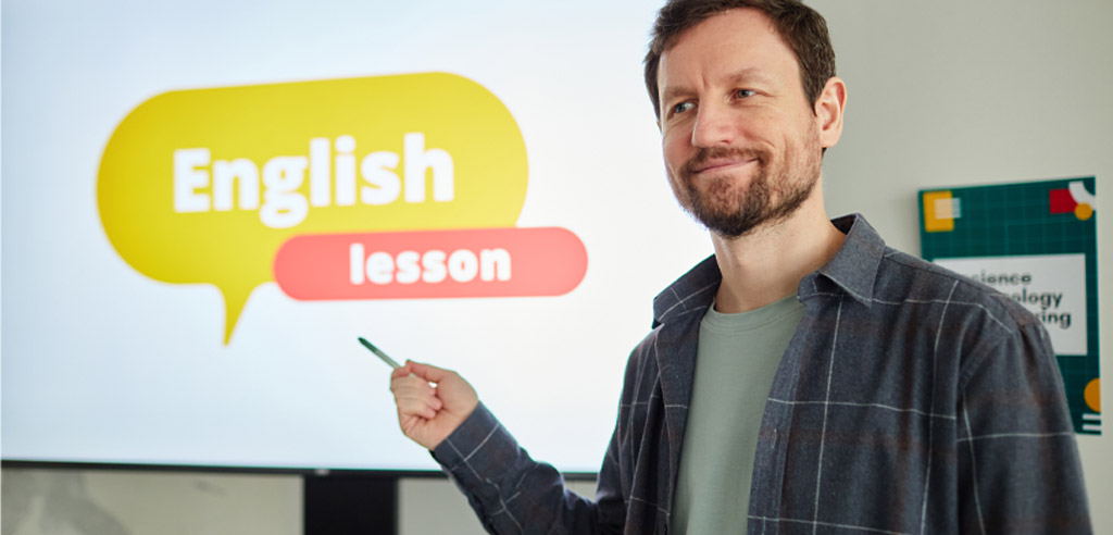 Male teacher standing in front of a board that reads "English lesson"
