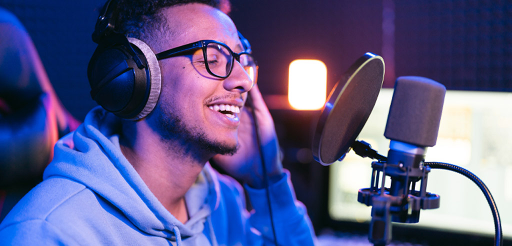 Voiceover artist smiling in front of a microphone while working on his voice acting side hustle