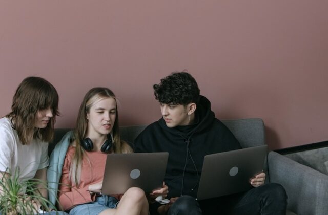 Three young people working on laptops.