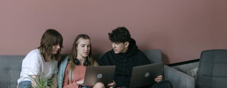 Three young people working on laptops.